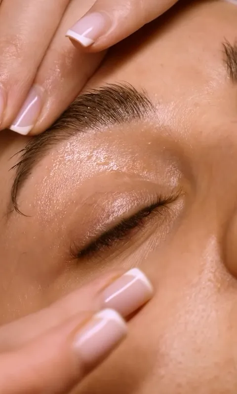 Merve Akkaya assessing the skin around a client's eye